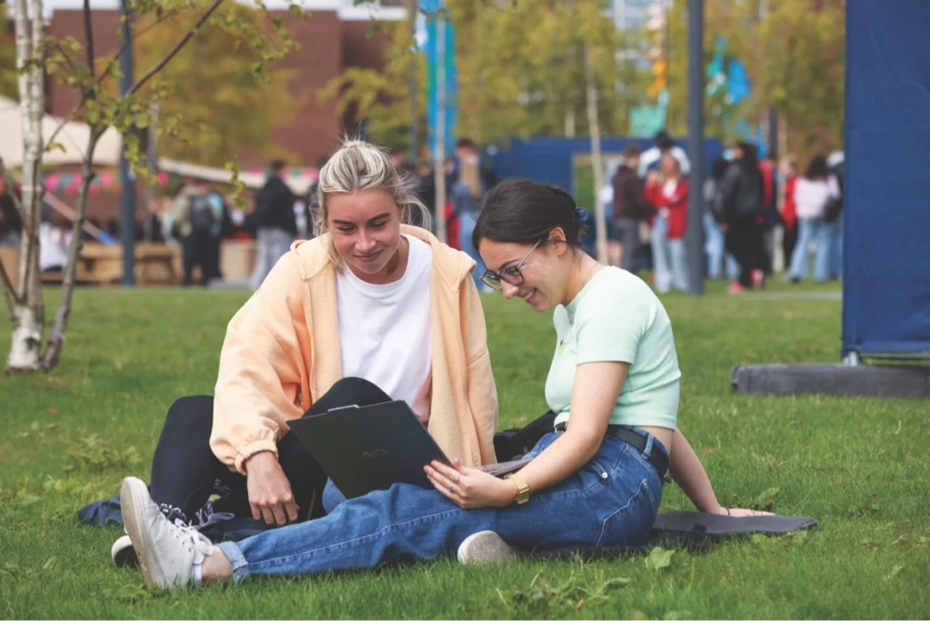 Two DCU students sitting on the grass chatting